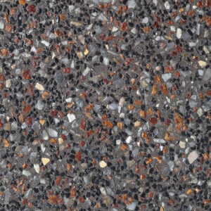 A close-up of dark grey exposed aggregate concrete featuring a dense mix of small black, translucent white, and rusty orange pebbles.