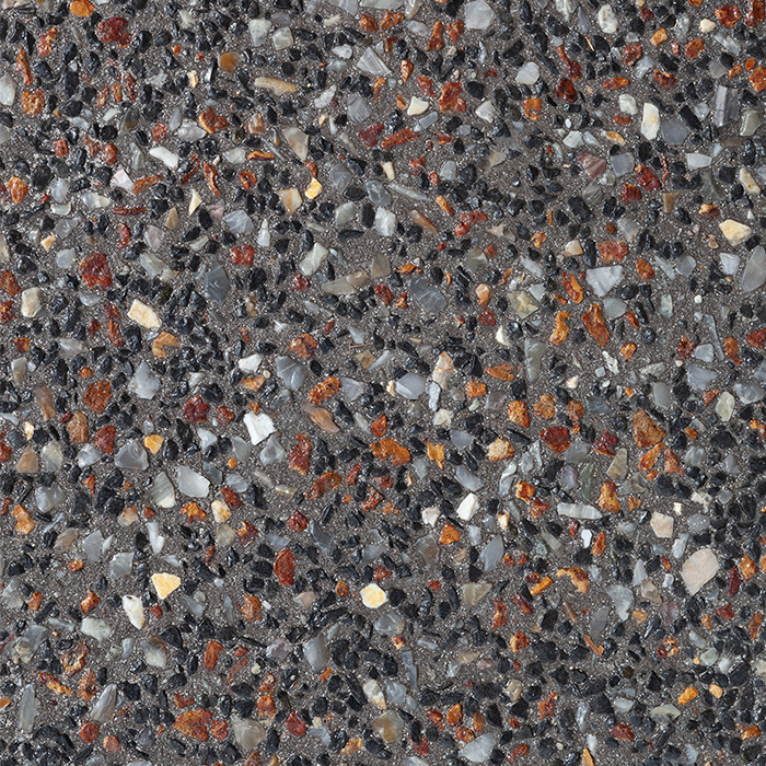 A close-up of dark grey exposed aggregate concrete featuring a dense mix of small black, translucent white, and rusty orange pebbles.