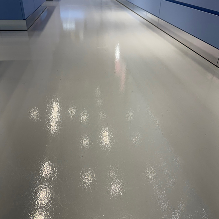 A highly polished, light grey floor in a hallway with light blue wall panels.
